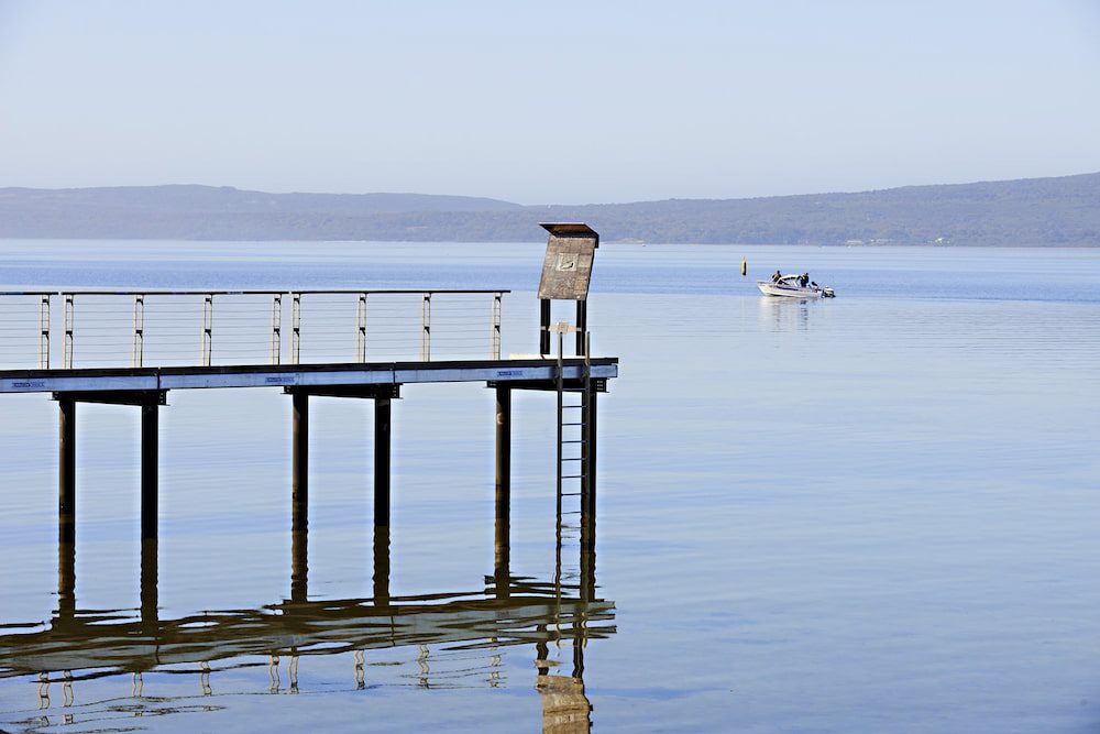 A glassy Princess Royal Harbour with a single little boat.